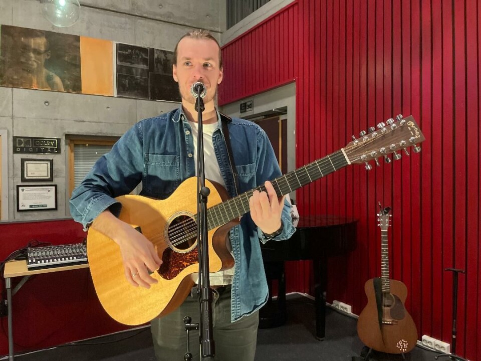 Ostoppele - både i foajéen og i grunnskolepensum Mann spiller på gitar og synger i mikrofon.