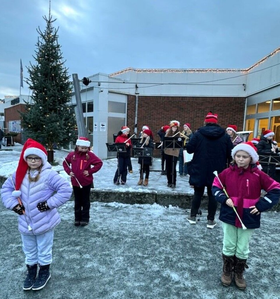 Surnadal skolekorps. Et korps med barn som spiller foran et butikksenter og en stor julegran.
