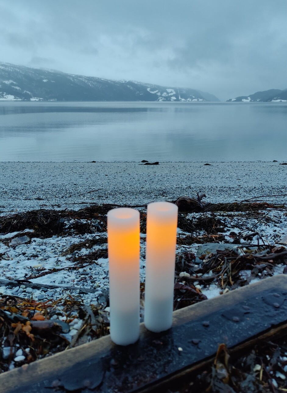 Bad på Kalkstranda. To badelys på 2. søndag i advent. To brennende lys på et rekkverk. Sjøen i bakgrunnen.