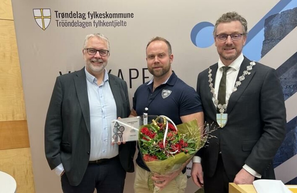 Prisvinner: Hallgeir Jordet fikk Trøndelag fylkeskommunes trafikksikkerhetspris 2024. Her står han sammen med fylkesordfører Tomas Iver Hallem (Sp) og leder i hovedutvalg for samferdsel Pål Sæther Eiden (H). Tre menn oppstilt for fotografering. En i midten med blomster. En med ordførerkjede.