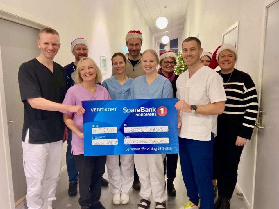 Årets julegave til Surnadal legesenter. Styret med spanderluer i anledning gaveoverrekkelsen. Foran f.v: Sivert Skuggevik, Gunn Eline Børmark, Rebecca Therese Bøe, Tonje Dahl Hjelkrem og Harald Grimstad. Bak f.v styremedlemmer i Sparebankstiftelsen: Nils Inge Aasgård, Jostein Kvendset, Karina Wigum, Mari Vattøy og Heid Snekvik. Blide leger og styremedlemmer med nisselue som holder en gavesjekk pålydende 912 500,-