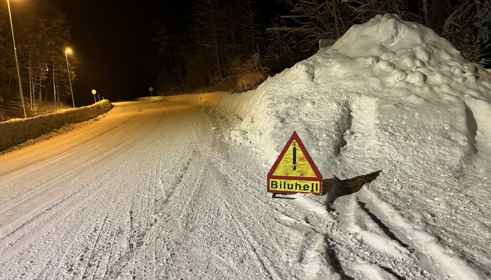 Stengt veg på Rindalsskogen på grunn av bilberging Et varselskilt om biluhell, som står i snøen i veikanten.