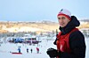 nærbilde av mann med jury-vest og walkie talkie og skistadion i bakgrunnen