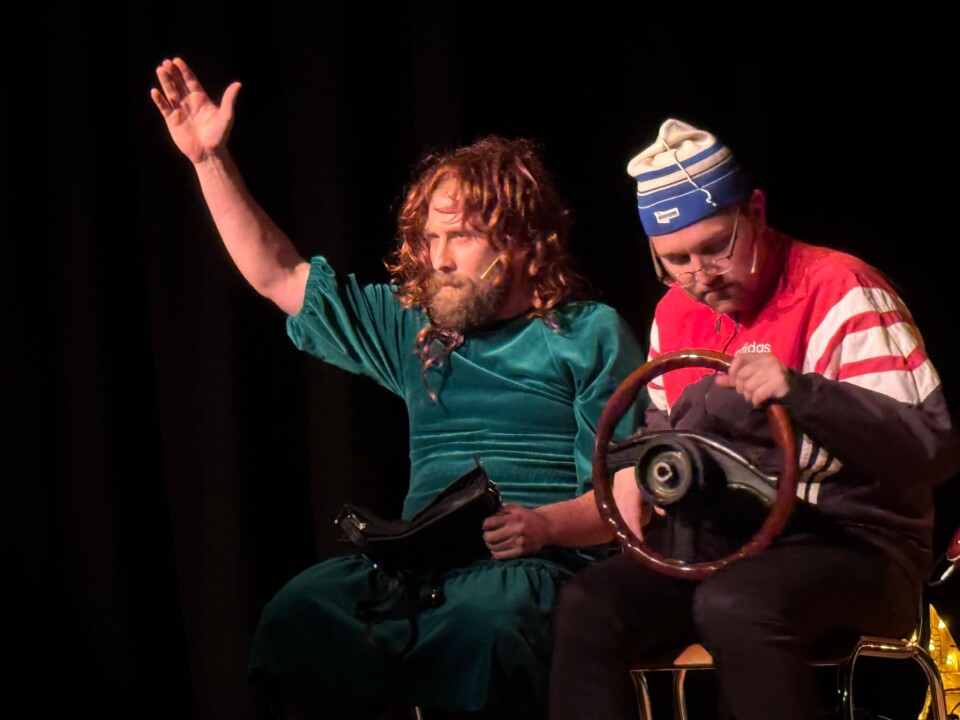 Kristian og Trond Ivar i velkjent stil. To skuespillere sitter ved siden av hverandre. En i kjole og en i treningsjakke. Den siste holder et ratt.