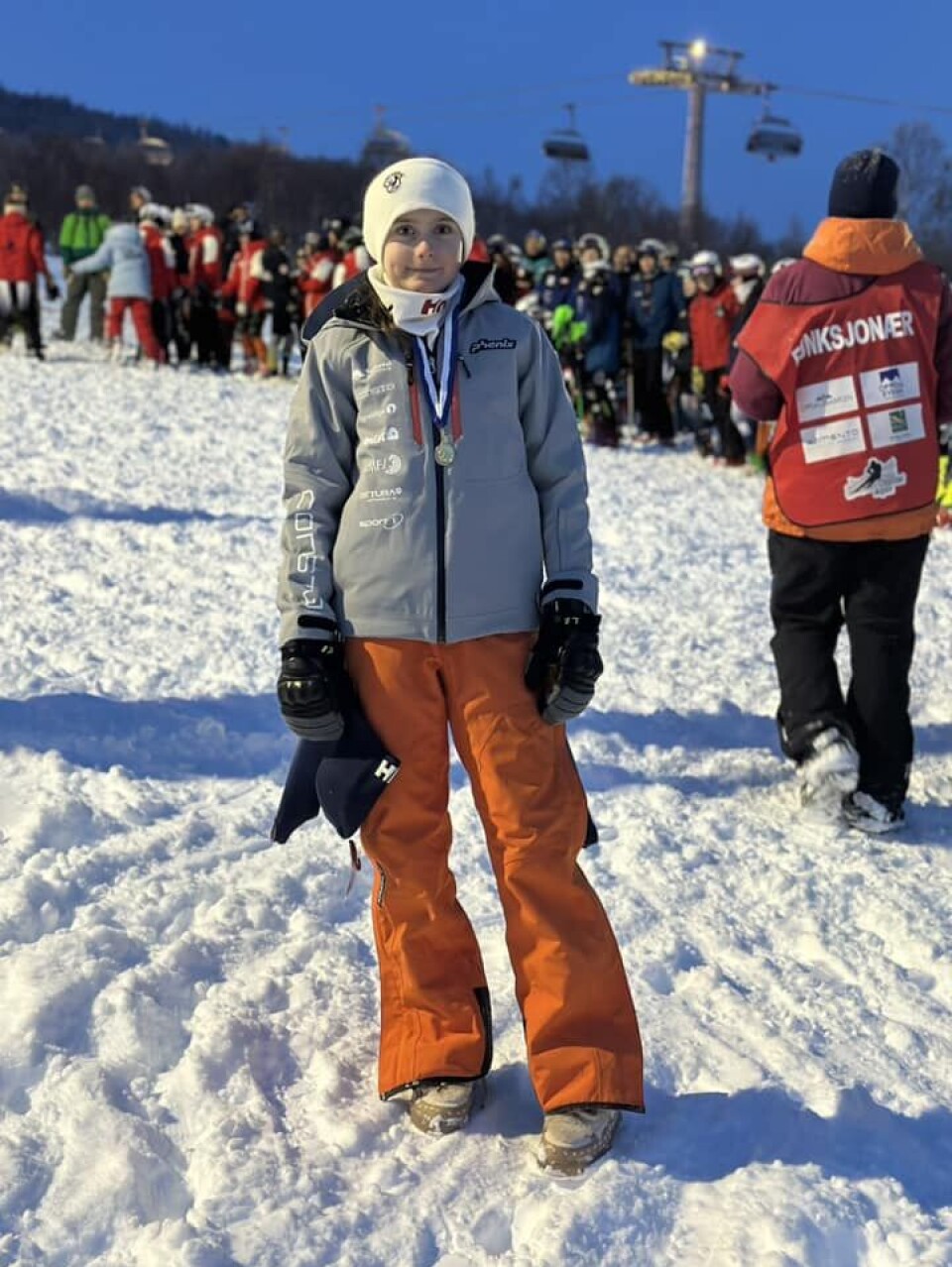 Bea Øie Nordvik U14. Jente med oransje bukse og grå klubbjakke med medalje