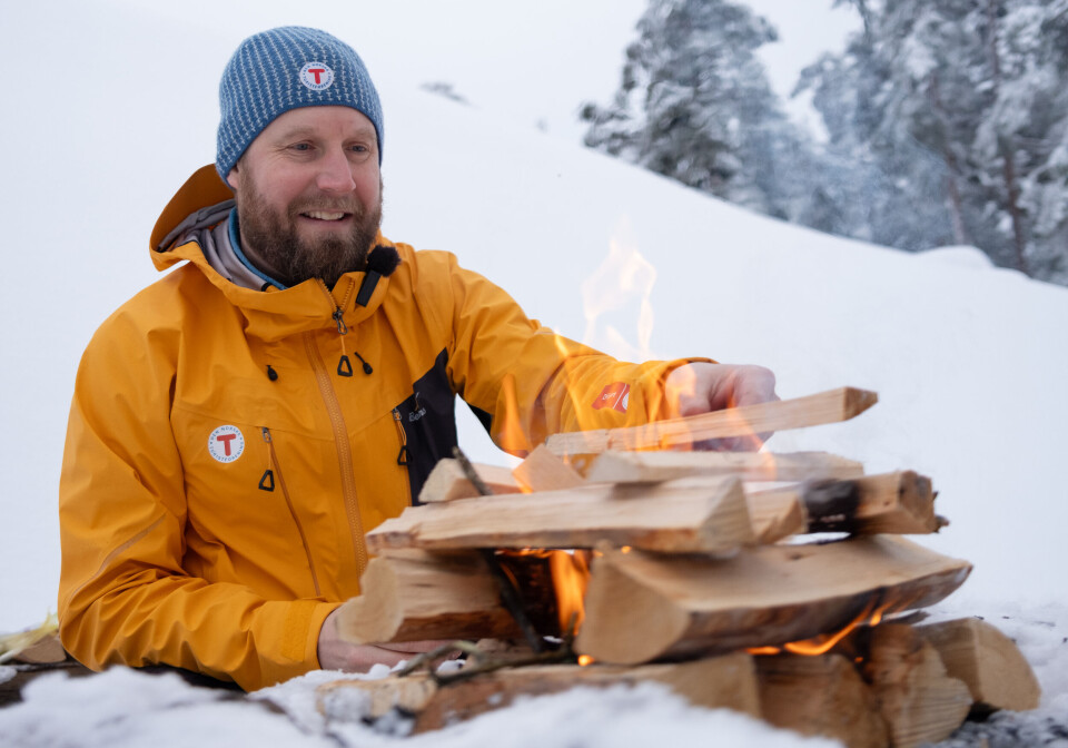 Mange lurer på hvordan lage et godt bål. DNT har tips og triks. En mann som fyrer opp et bål.