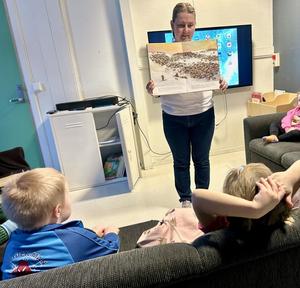 Anita Våbenø viser frem bilder fra ei samisk barnebok. Dame som holder opp ei bok med bilde av masse reinsdyr