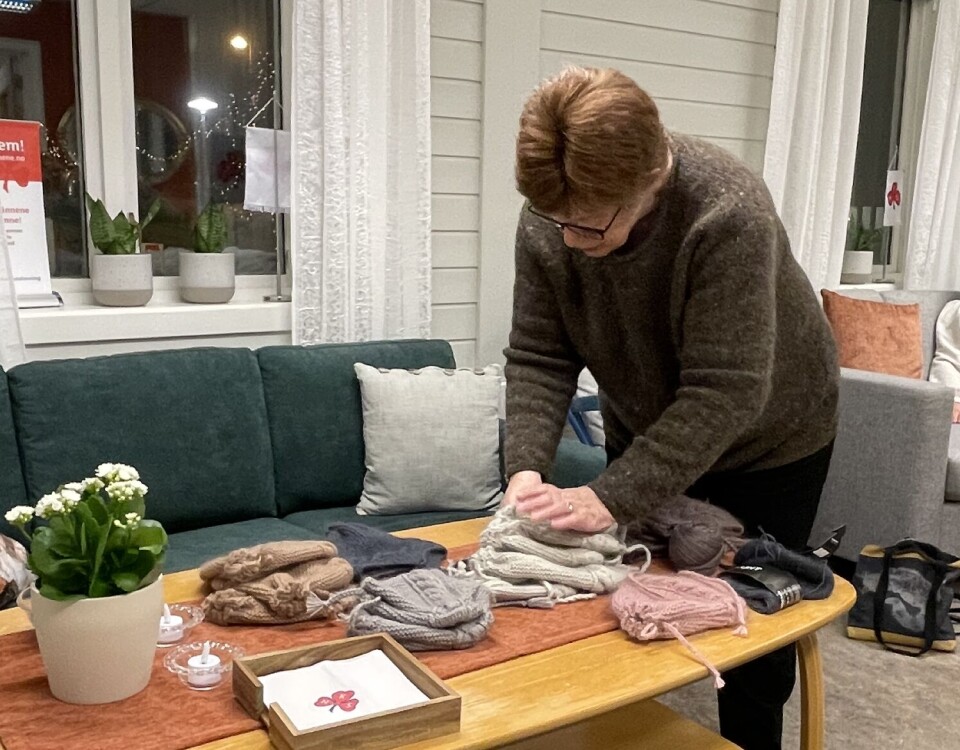 Gjennomgang av antall luer for nybarntreffet i mars En kvinne står bøyd over et bord og ser over strikkede luer.