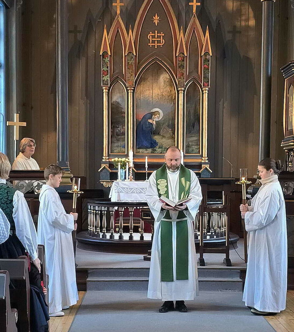 Evangelielesinga: Prost Vidar flankert av konfirmantane Syver og Emilie med prosesjonslysa. I klokkarstolen: Randi V. Bøe. En prest og noen konfirmanter foran i ei kirke under en gudstjeneste.