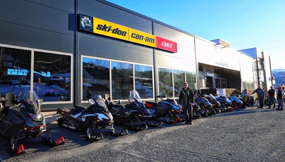 Daglig leder i RBL, Jon Moen, viser frem 2026-modellen som kan bestilles etter dine spesifikasjoner for levering til neste snøsesong. Jon står foran 8-10 skutermodeller som står på linje foran butikkvinduenen.