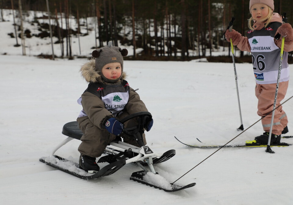Godværet kom til Rindalsmesterskapet på Igltjønna Et barn som sitter på en rattkjelke, og et barn som går på ski.