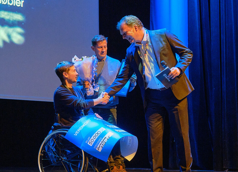 Daniel og Jarle Fiske mottar utviklingsprisen fra Allan Troelsen. Tre menn på en scene.
