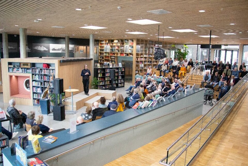 Osen fanger publikums oppmerksomhet. Mange mennesker sitter vendt mot en mann i finklær og vest.