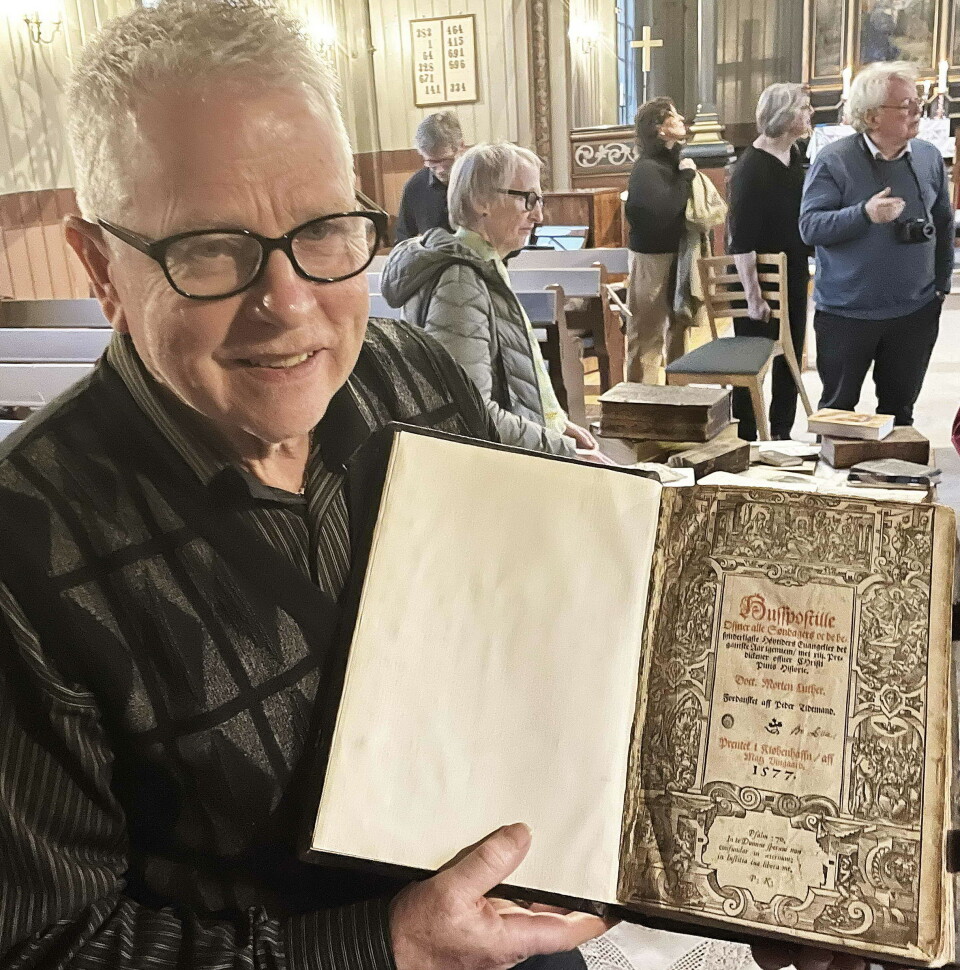 Arne Drøpping med Luther-postillen trykt i 1577. En mann som holder fram ei veldig gammel bok.