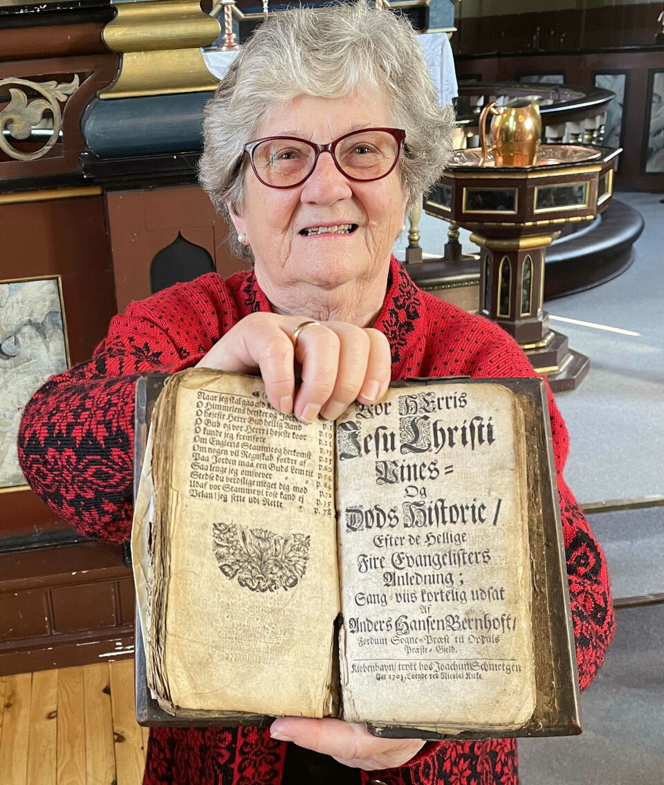 May Holten med Bernhoft-klenodiet frå 1703. Ei dame med ei veldig gammel bok foran seg.