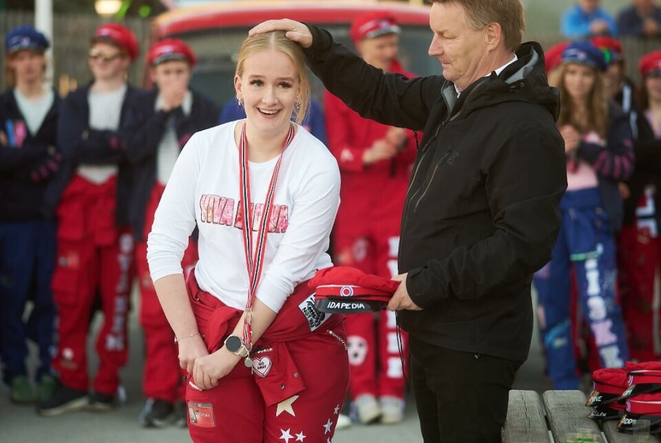 Visepresident Ida Mo Mann med hånden på hodet til en russ. Mannen har en russelue i andre hånden. Russ og russebil i bakgrunnen.