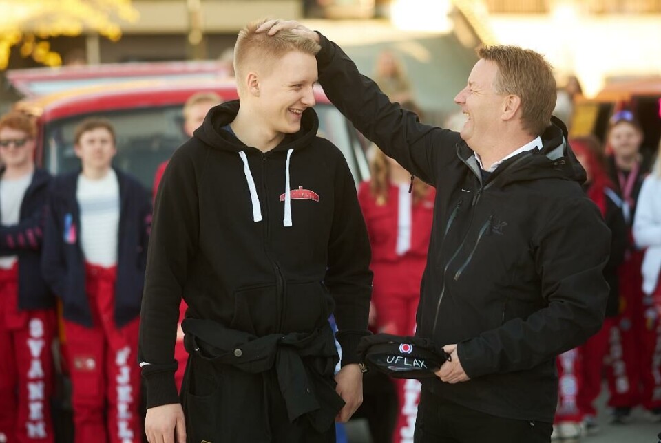 Uflax eller ei. Her er stemningen på topp. Nå er russen klar for russetid. Mann med hånden på hodet til en russ. Mannen har en russelue i andre hånden. Russ og russebil i bakgrunnen.