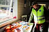 Mann i caps og gul vest legger premiene på bordet under vinduet.