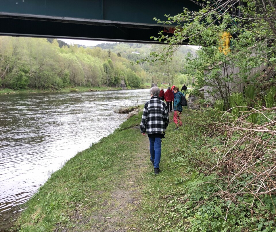 folk som går på en sti under ei bru langs ei elv