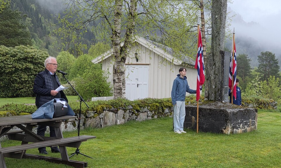 Leiar i Todalen historielag, John Moe, las opp namna på dei tjue frå Todalen som under felttoget våren 1940. En mann som står og taler ved et minnesmerke. To unge gutter holder hvert sitt norske flagg.