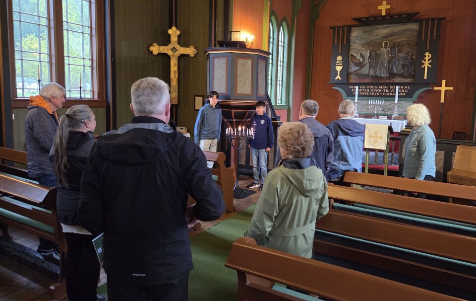 Konfirmantane Trygve Aleksander og Jens Sancho tente tre lys til minne om dei tre falne frå Surnadal kommune. Flere mennesker i et kirkerom.