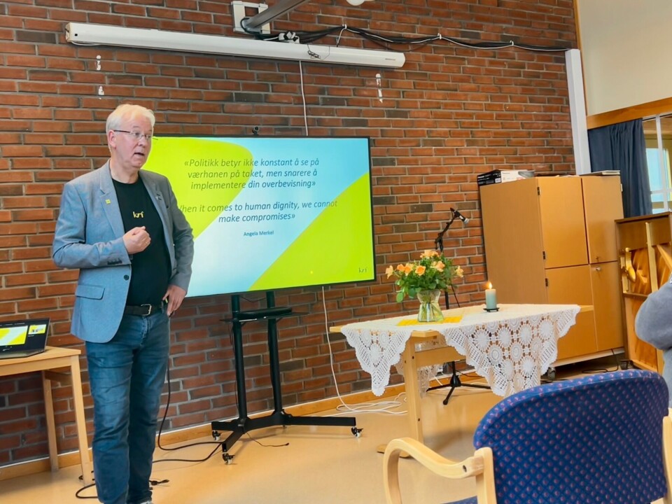 Helge Kjøll har lang politisk erfaring, og delte mange inspirerende tanker med de fremmøtte. Sitater av hans politiske forbilde Angela Merkel på skjermen. Mann som holder foredrag.