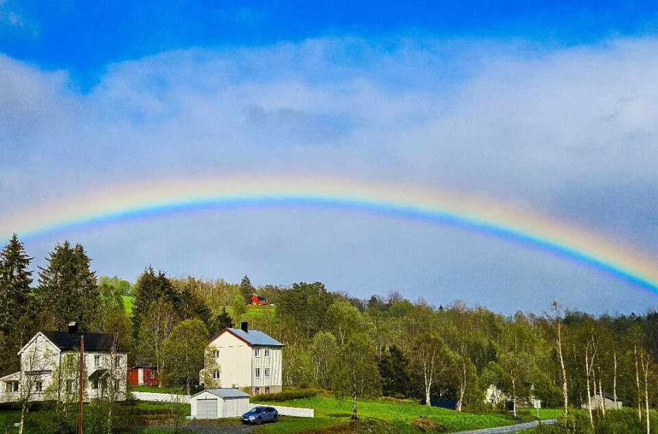 Rønningen. Sol og regn om en annen. Tre hus med en regnbue over.