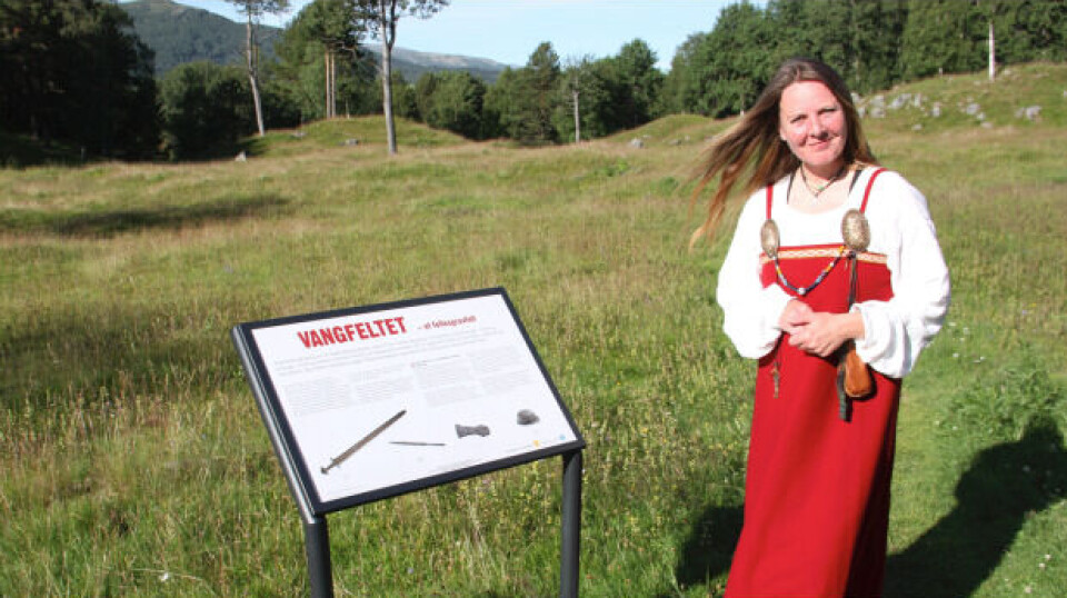Anne Lise Fløttumm arkeolog og tidligere leder for Oppdalsmuseet, ved Vangfeltet. Ei dame i vikingdrakt, ved ei informasjonstavle.