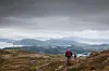 To menn på vei ned fra fjellet med utsikt over fjell og fjord