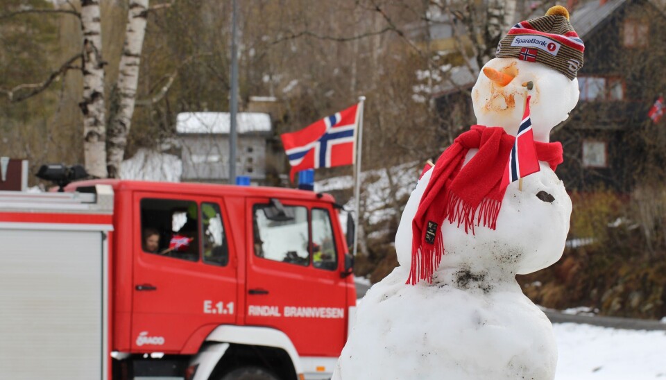 ¨¨ En snømann med norsk flagg, og en brannbil pynta med norsk flagg i bakgrunnen.