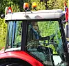En person som sitter inne i en traktor og kjører. Traktoren er pyntet med norske flagg på taket.