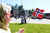 Ei dame som vifter med et norsk flagg foran en folkemengde på 17. mai.