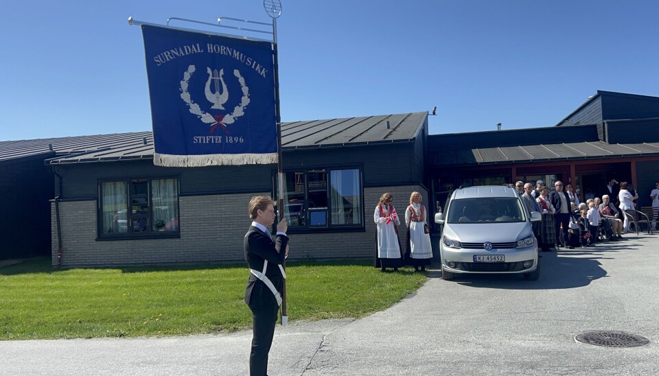 mann med uniform og flagg 'surnadal hornmusikk'