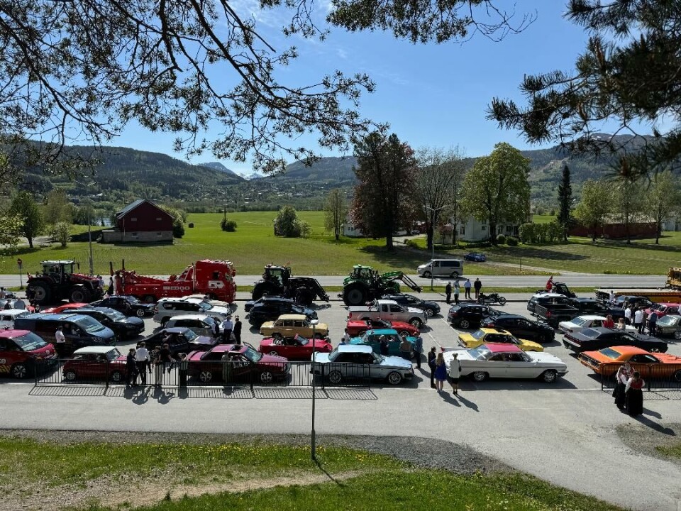Nordmøre gatebilklubb hjalp til under parkering og klargjøring før start da Surnadal AmCar Club arrangerte biltog 17. mai. Bildet er tatt fra Surnadal barne- og ungdomsskule hvor vi ser bare en brøkdel av alle kjøretøyene som var oppmøtte før start. Masse biler og mennesker rundt om.