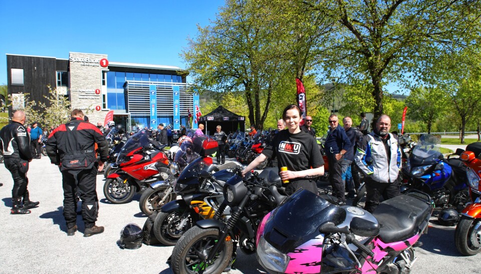 Selv om det er trivelig å møte gamle kjente for ei voksen motorsykkeldame, så er det vel en viss forgubbing i miljøet. Derfor er det fint å møte Kristine Meslo Sæter som er aktiv i styret i Surnadal MC-klubb og ungdomskontakt for NMCU. Her står hun ved 3 av sine 4 motorsykler. Dame i svart nmcu-tskjorte står og holder en sort shopper og har Honda CBR 600 bak og framfor seg.