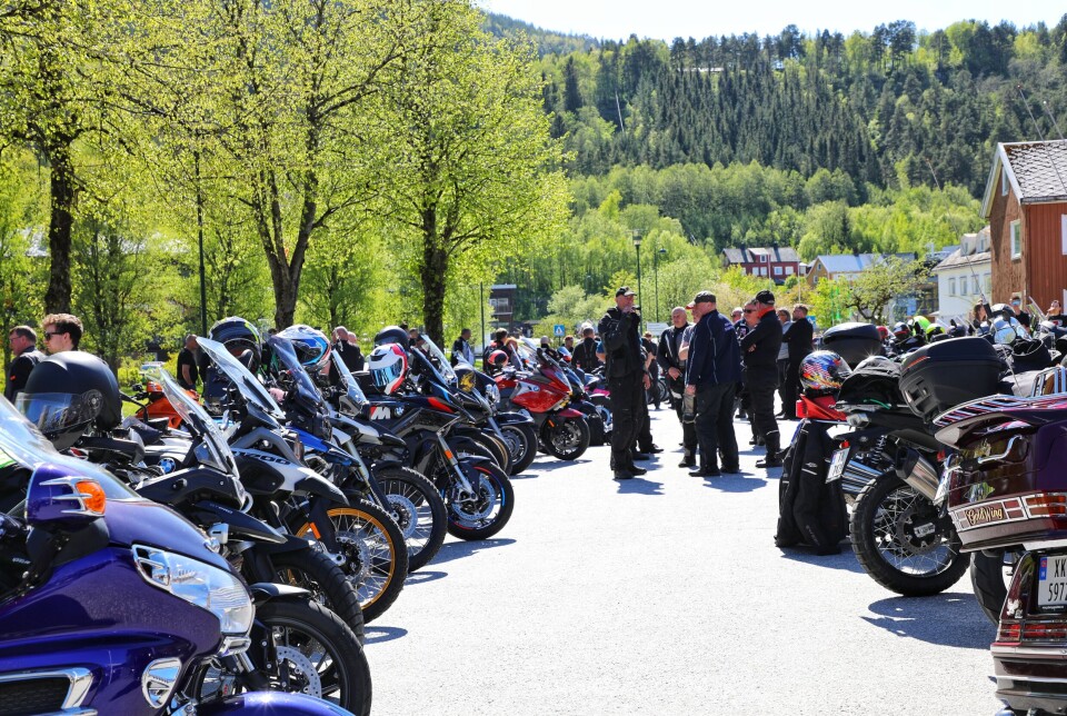 For noen var dette første samling med gamle kjente etter vinteren. fotografen har stilt seg mellom to rader med parkerte motorsykler. grupper av folk innimellom.