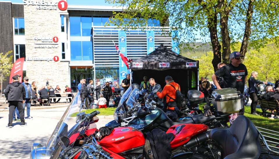 NMCU var tilstede på arrangementet ved Dordi Settemsdal. Rød Ducati motorsykkel i front med flere parkert mellom denne og sort partytelt med nmcu-logo