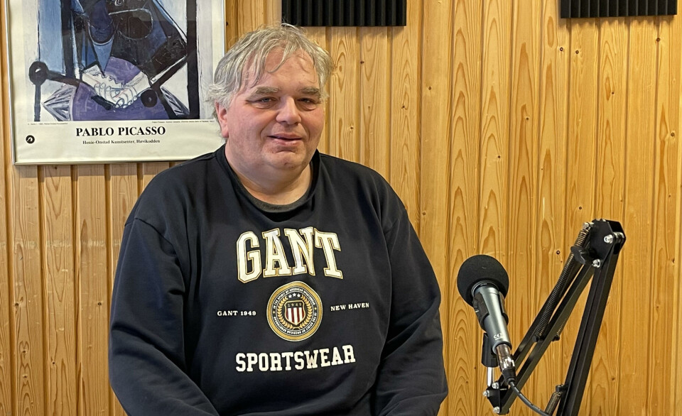 Hans Torslett er gjest i Trollheimspodden En mann i mørk genser sitter ved en vegg. Foran seg har han en microfon