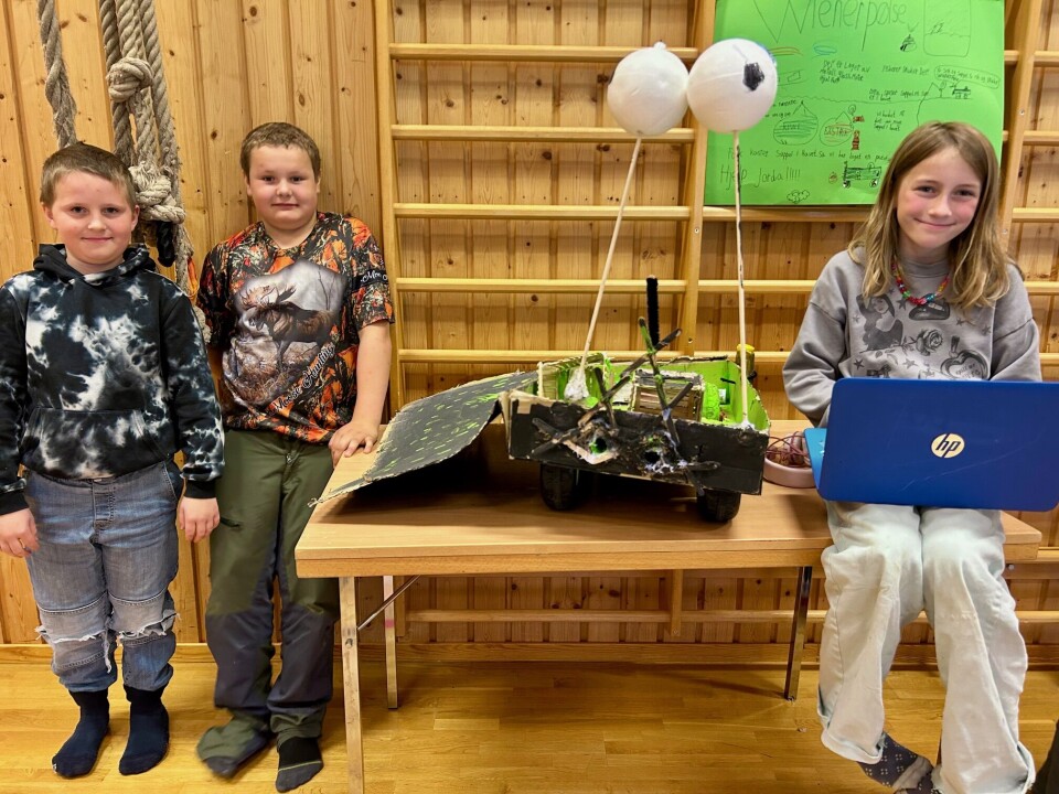 Håkon, Oliver og Magnhild viser stolt frem sin prototype av en undersjøisk søppelplukkerobot. Unger og en 'robot'