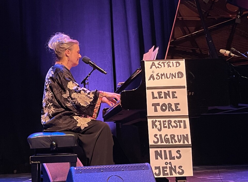 Bjørnov legger opp til allsang i salen med en låt om våre nye ministere. En dame sitter ved et flygel