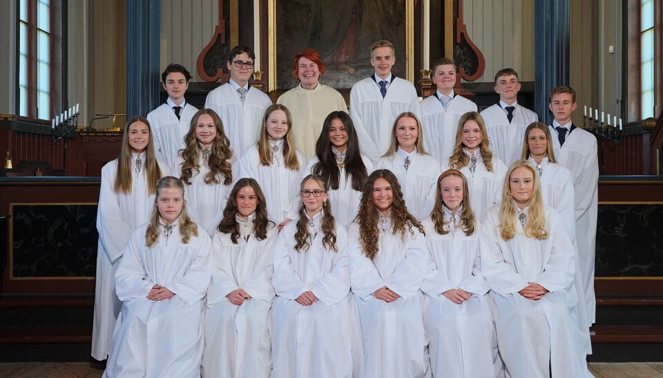 Konfirmantene i Rindal kirke Ei gruppe kappekledde konfirmanter og en prest oppstilt til fotografering i kirka.