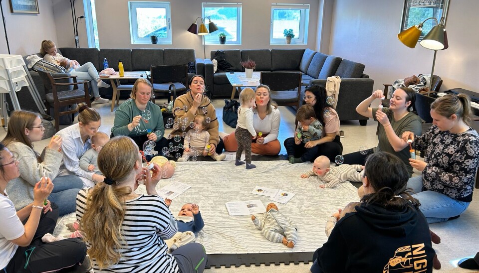 Mange på babysang forrige uke og topp stemning! Ei gruppe voksne og barn som sitter i ring på et teppe på gulvet.