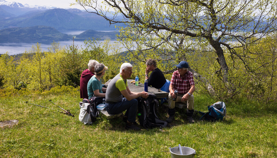 Solide benkar, stolar og bord av stein på Vanghytta. Mennesker som kviler ved ein benk