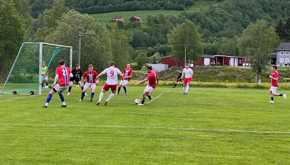 Rindal IL tok i mot Nationalkameratene hjemme på Rinnvollen onsdag. Kampen endte med poengdeling. Fotballspillere på gressbane i røde og hvite overdeler foran mål med keeper i sort overdel.