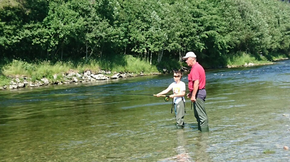 Laksefiske i Advokaten To mennesker som står i elva, en fisker.
