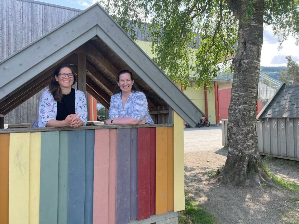 Årets og fjorårets leiar i FAU Surnadal barne- og ungdomsskule 1.-7. trinn, Brit Roaldset og Eli Vullum Kvande, i det gamle leikehuset fra Øye skule som blei oppfriska med mange flotte fargar under fjorårets dugnad. To damer står i en liten bygning som er malt i ulike farger.