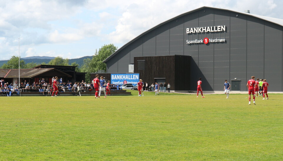 stor hall bak fotballbane med fotballspillere på