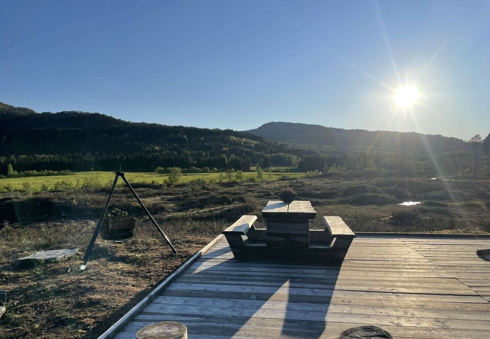 Kavlvegen. benk og bålpanne med sol i bakgrunnen