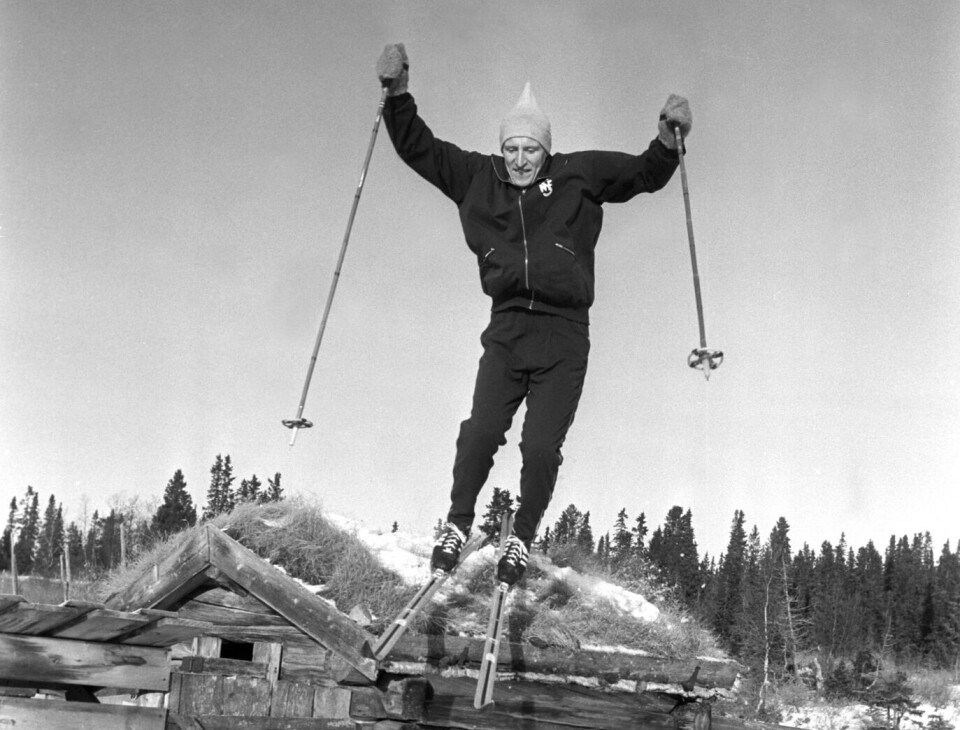 Langrennsløper og visesanger Ole Ellefsæter. Mann med ski hopper fra stabbur - svart hvitt bilde