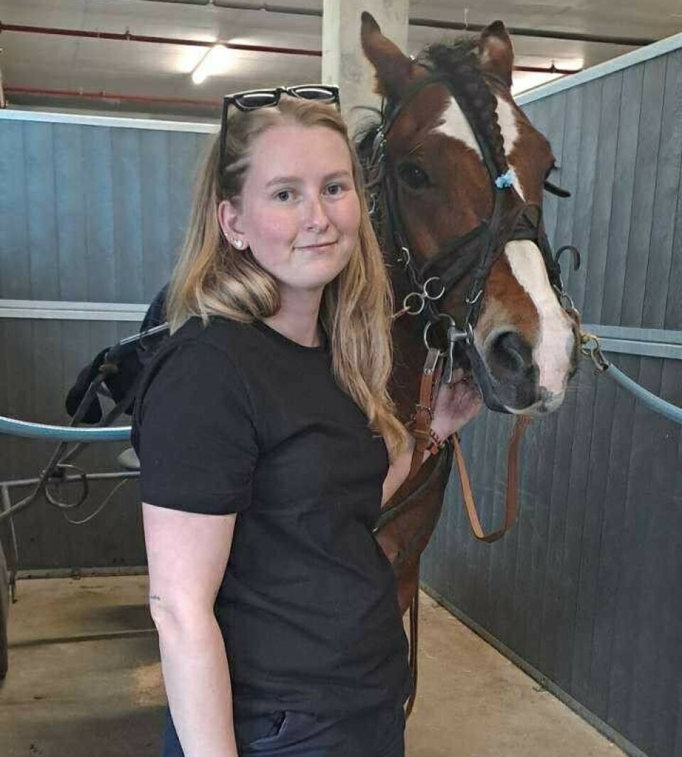 Oppasser Embla Røen Fosseide med gromguten Stormare. Ei ung dame som står ved siden av en travhest.